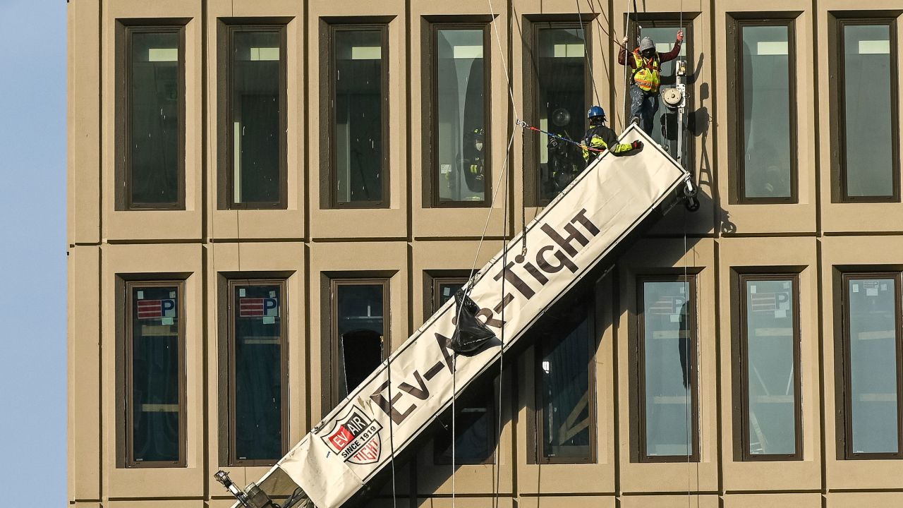 A worker stands on the end of a dangling scaffold as he waits to be rescued Wednesday.