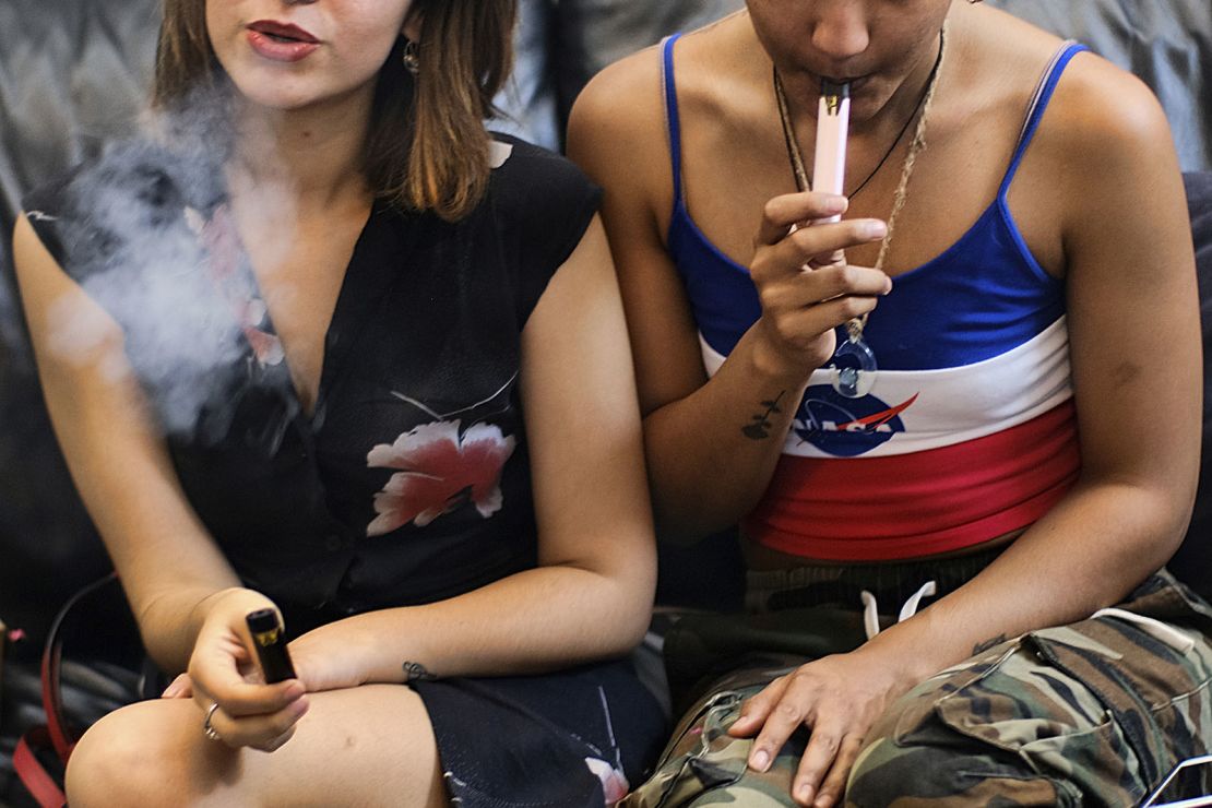 In June 2019, two women smoke cannabis vape pens at a party in Los Angeles. A national outbreak of deadly lung illnesses tied to vaping transpired that year. 