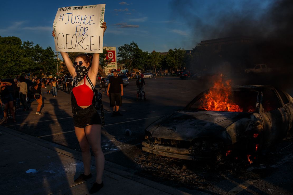 A protester hold sign board "Justice for George" into a fire outside a Target store near the Third Police Precinct on May 28, 2020 in Minneapolis, Minnesota, during a demonstration over the death of George Floyd.