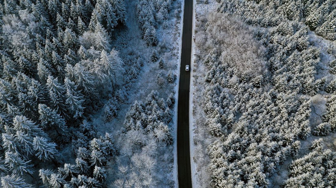 <strong>Ruderatshofen, Germany</strong>: A solitary car drives through a large snow-covered forest in Bavaria. 