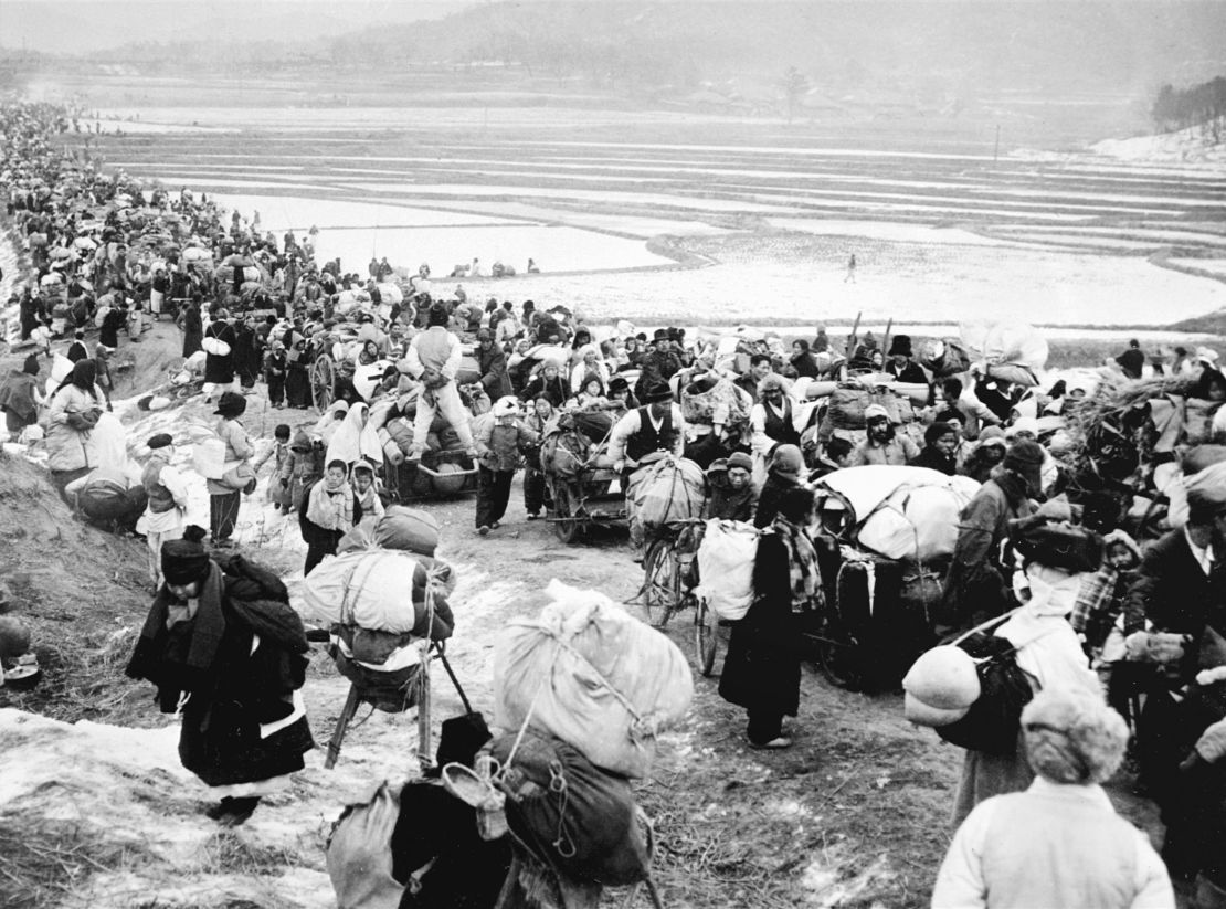 Unlocated picture taken January 18, 1951, shows Korean refugees passing frozen rice fields as they fled to the south.