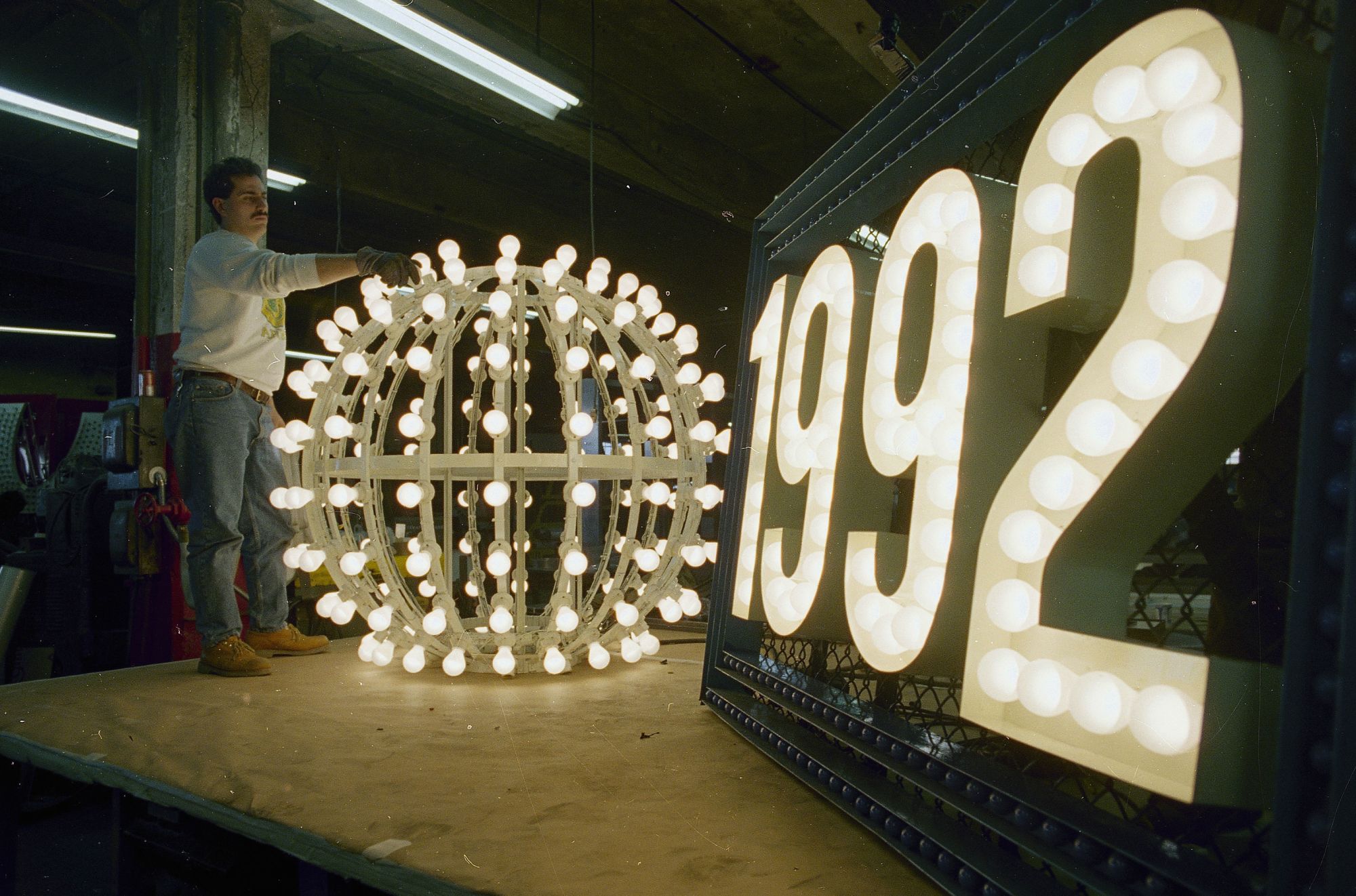 Phil Cicio, an electrician at Artkraft Strauss Sign Corporation, checks the lights on the ball that will drop in New York's Times Square on New Year's Eve, at the company's warehouse in New York, Dec. 26, 1991.  The ball weighs 200 pounds, is six feet in diameter and contains 180 white outdoor lamps.  The tradition dates back to 1907 when the first ball was lowered from the top of One Times Square, then the New York Times building.