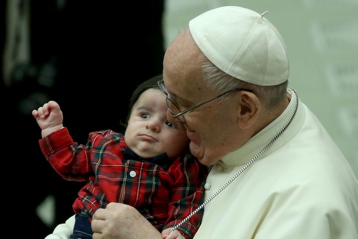 Pope Francis holds a child from the audience as Vatican employees gather for Christmas greetings in Vatican City on Monday, December 21, 2020.