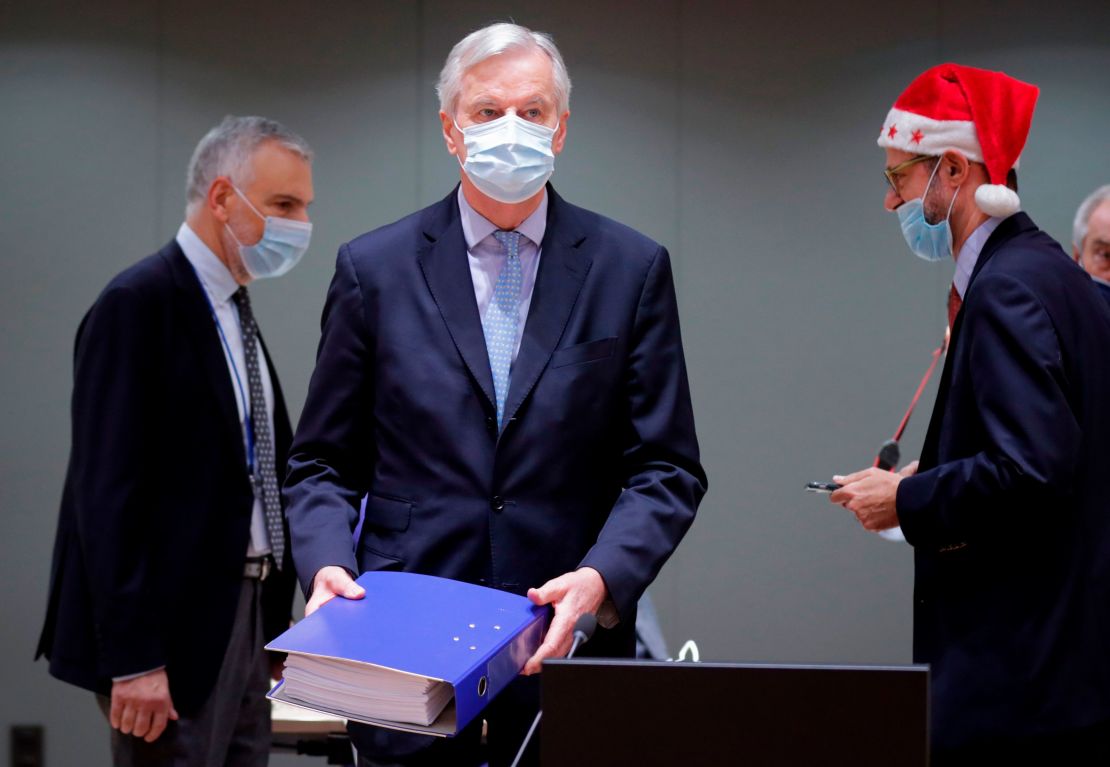 Barnier (C) lugs a folder containing the trade deal into the meeting with EU nation envoys in Brussel on Friday. 