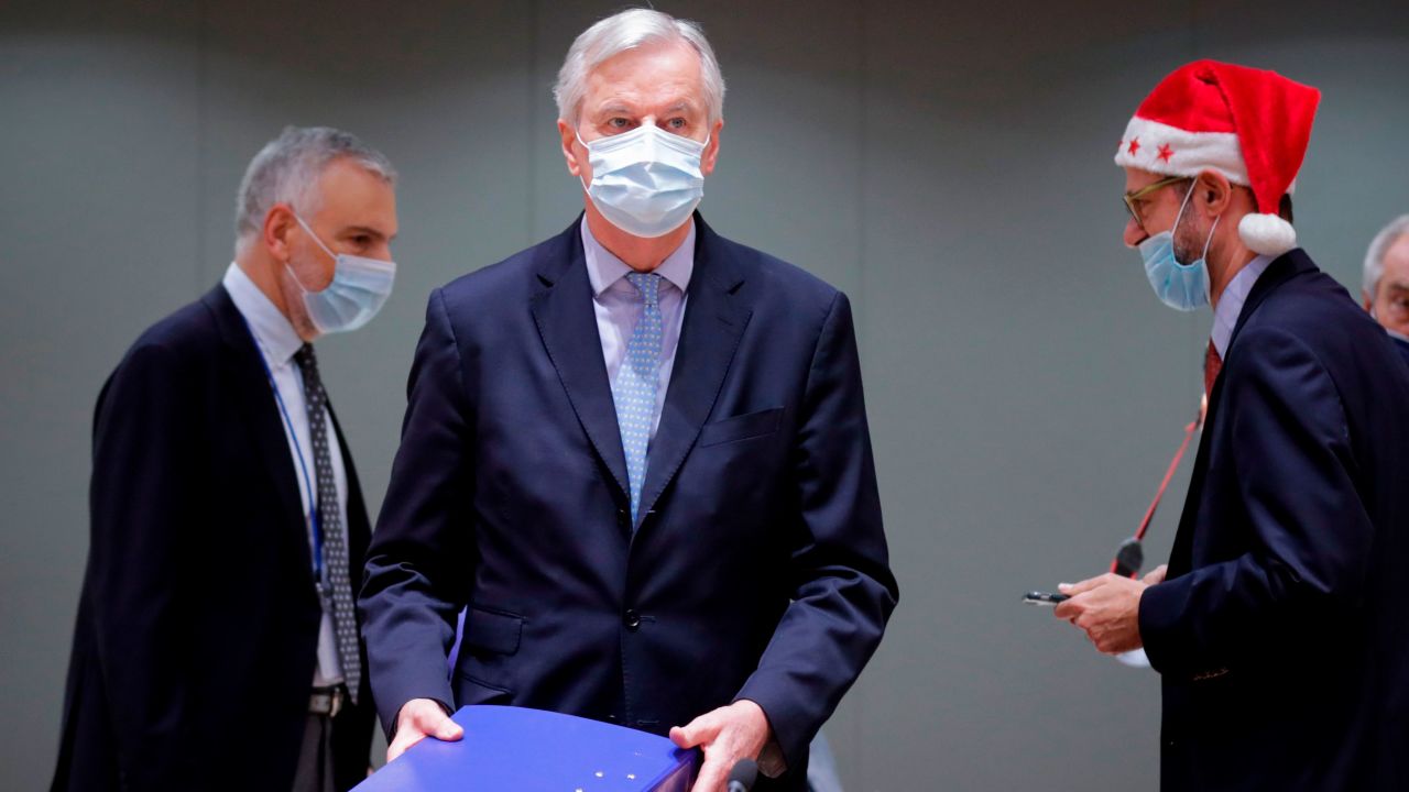 Barnier (C) lugs a folder containing the trade deal into the meeting with EU nation envoys in Brussel on Friday. 