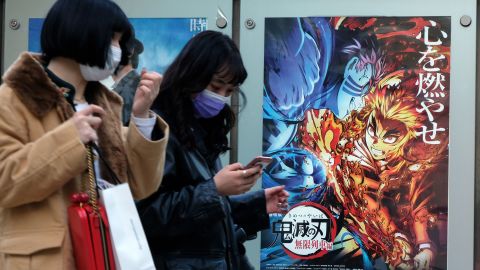 Pedestrians walk past a poster promoting the anime movie "Demon Slayer" at a cinema in Tokyo. 