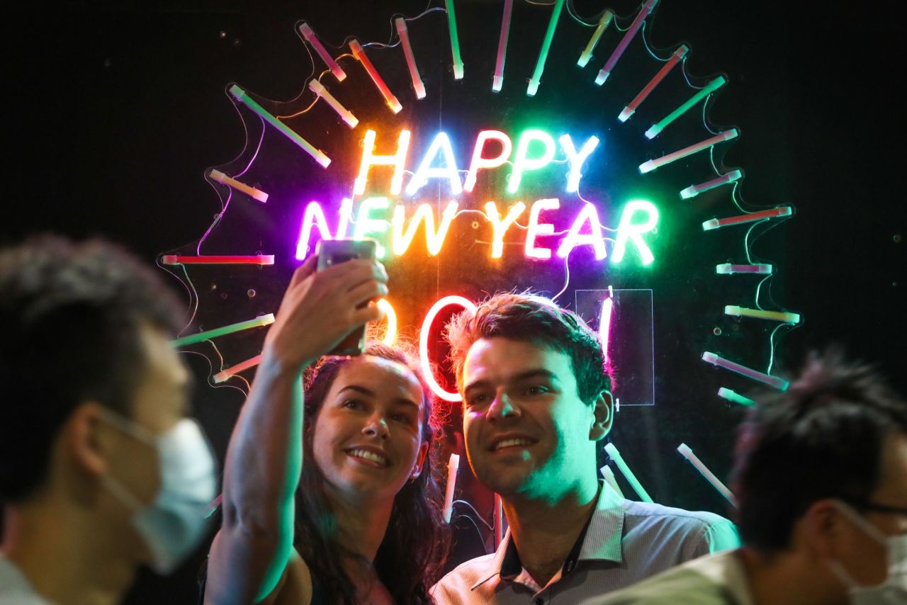 People take a selfie in front of a neon sign in Melbourne.