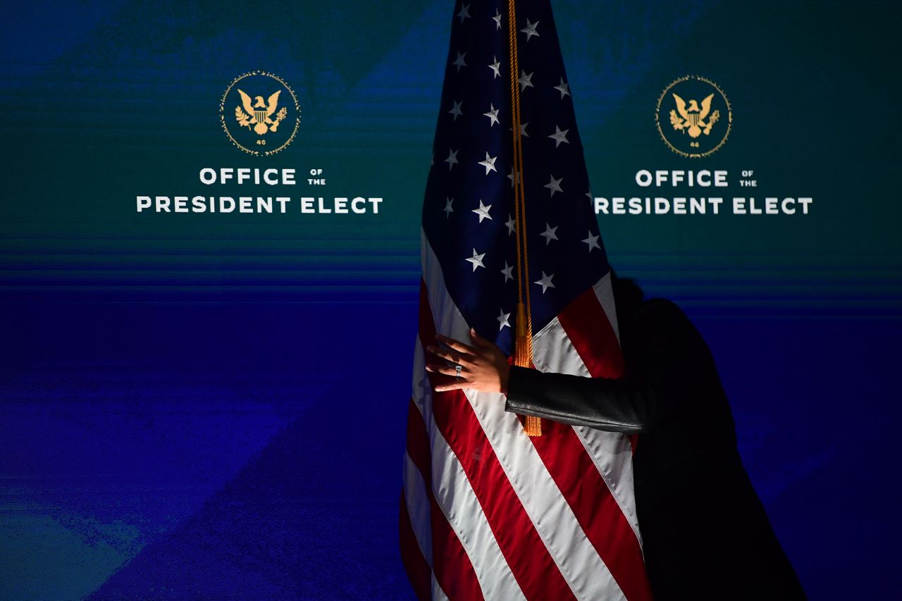 A staff member straightens an American flag before US President-elect Joe Biden delivered remarks in Wilmington, Delaware, on Monday, December 28.