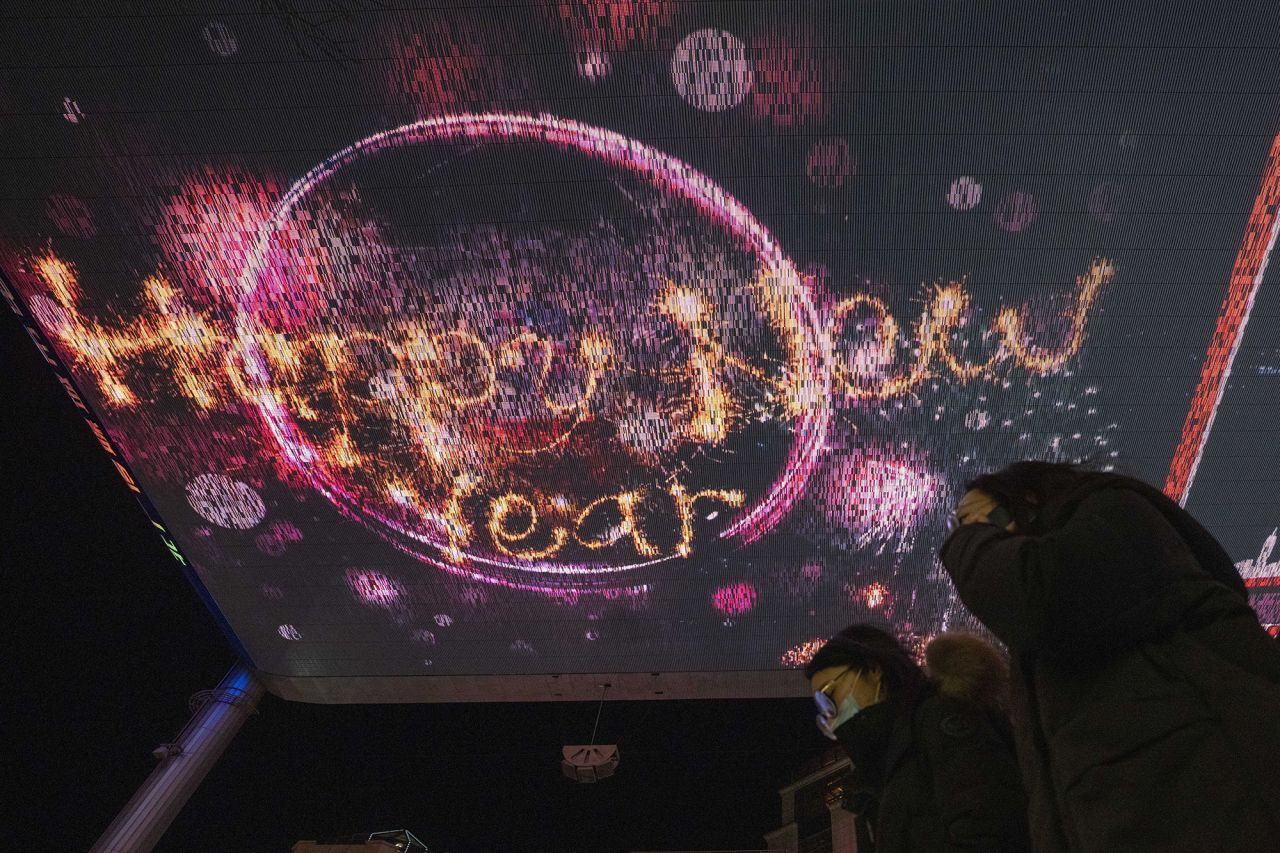 People in Beijing walk past a display that reads "Happy New Year."