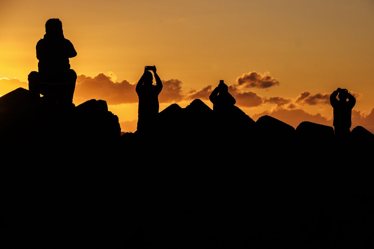 People take pictures and watch the first sunrise of the new year from a beach in Fujisawa, Japan.