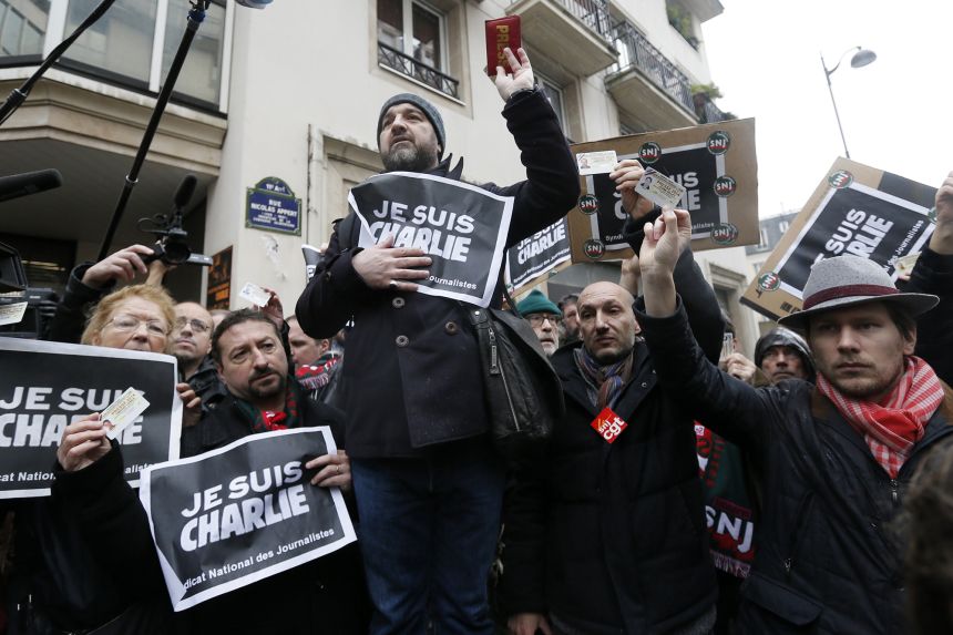 Journalists hold placards which read "I am Charlie" and their press cards during a minute of silence in front of the Paris offices of weekly satirical newspaper Charlie Hebdo in Paris January 8, 2015 the day after a shooting at their offices.