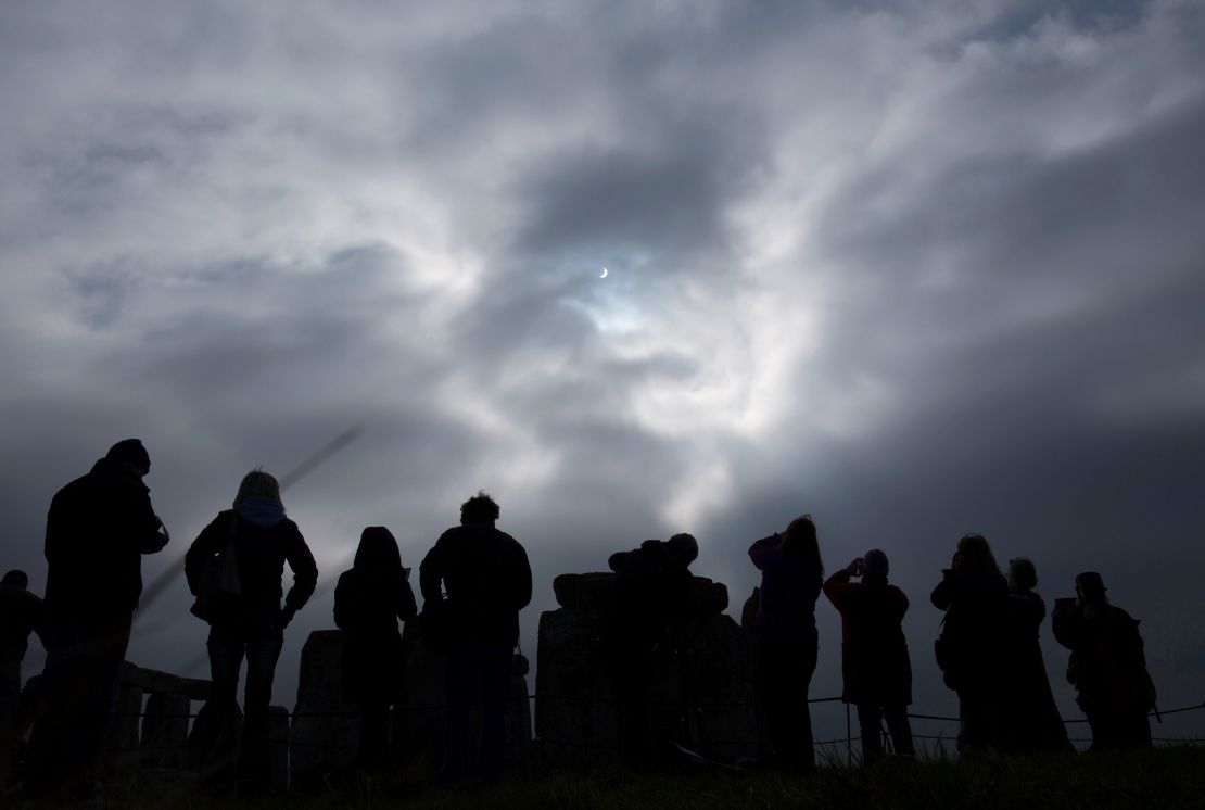 A small gap in a layer of overcast clouds allows visitors view a solar eclipse from Stonehenge in southern England on March 20, 2015.