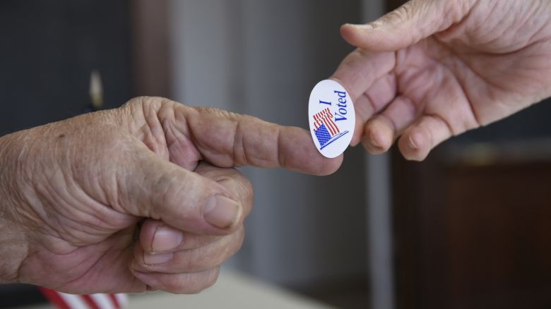 Poll worker Kenny Smith hands a sticker to a voter on Super Tuesday in Stillwater, Oklahoma on March 1, 2016.