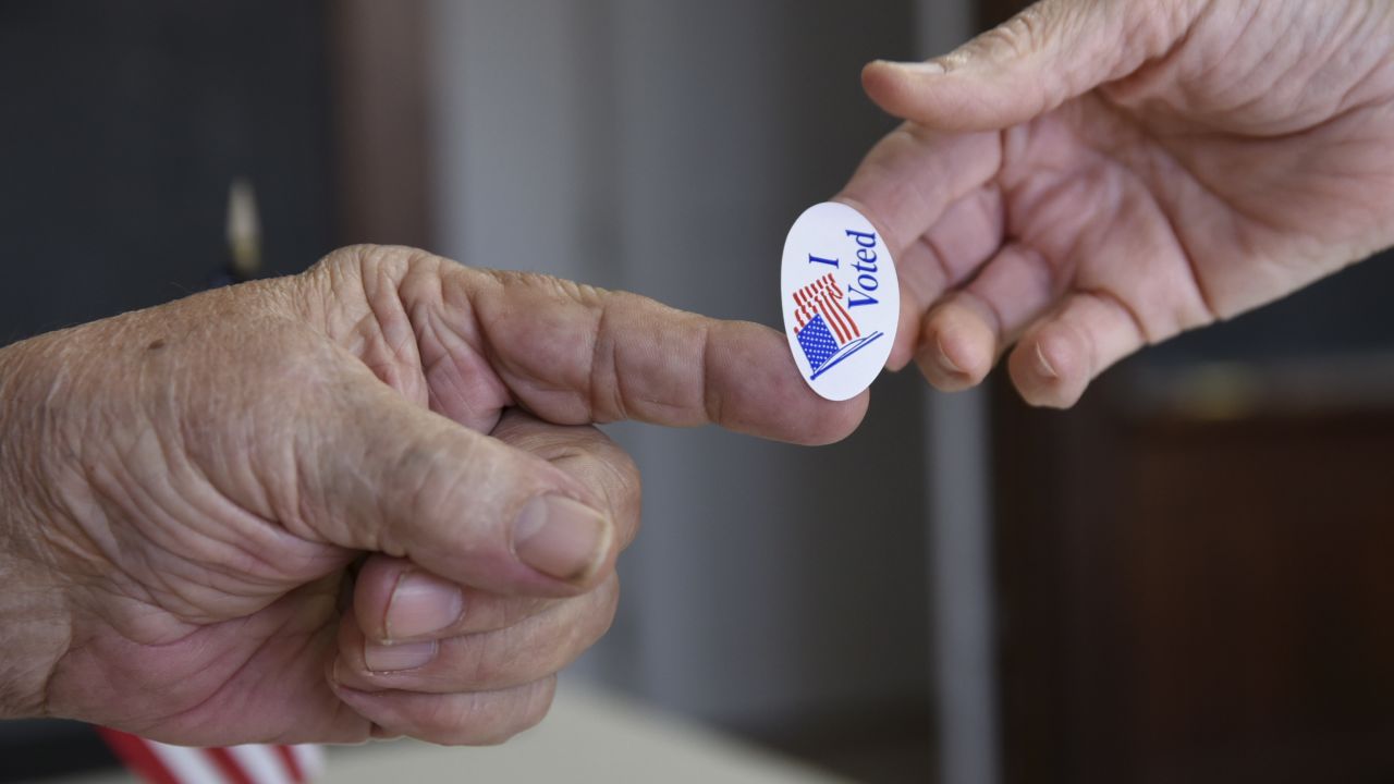 Poll worker Kenny Smith hands a sticker to a voter on Super Tuesday in Stillwater, Oklahoma on March 1, 2016.