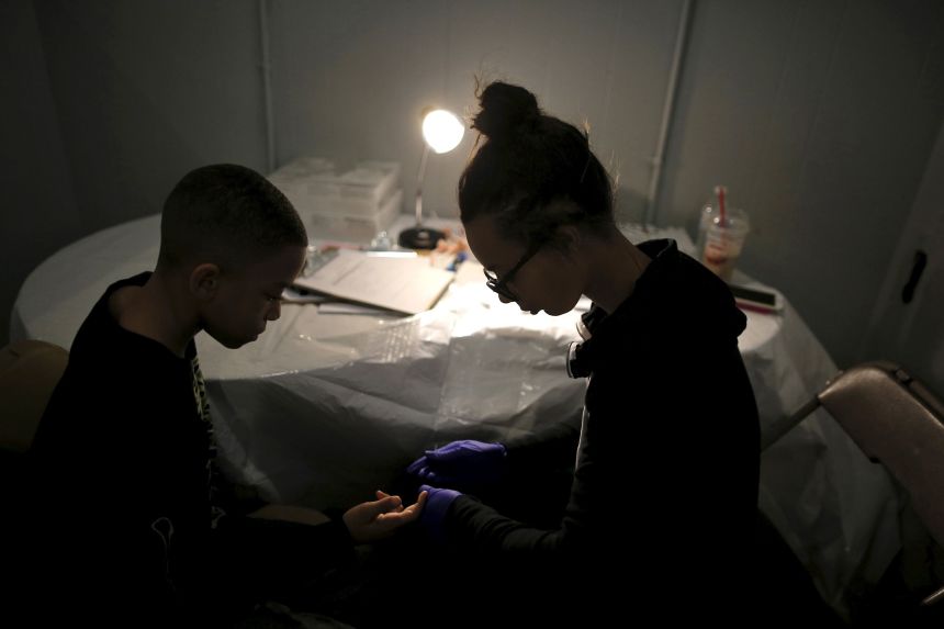 Brandon Fant, left, gets his blood tested for lead levels by Lashae Campbell at a clinic in Flint, Michigan, on March 6, 2016.