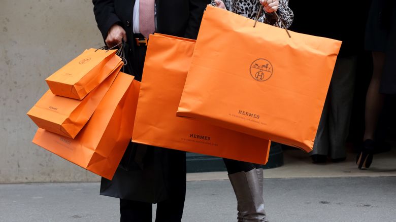A couple walk with Hermes shopping bags as they leave a Hermes store in Paris, France, March 21, 2013.   REUTERS/Philippe Wojazer/File Photo