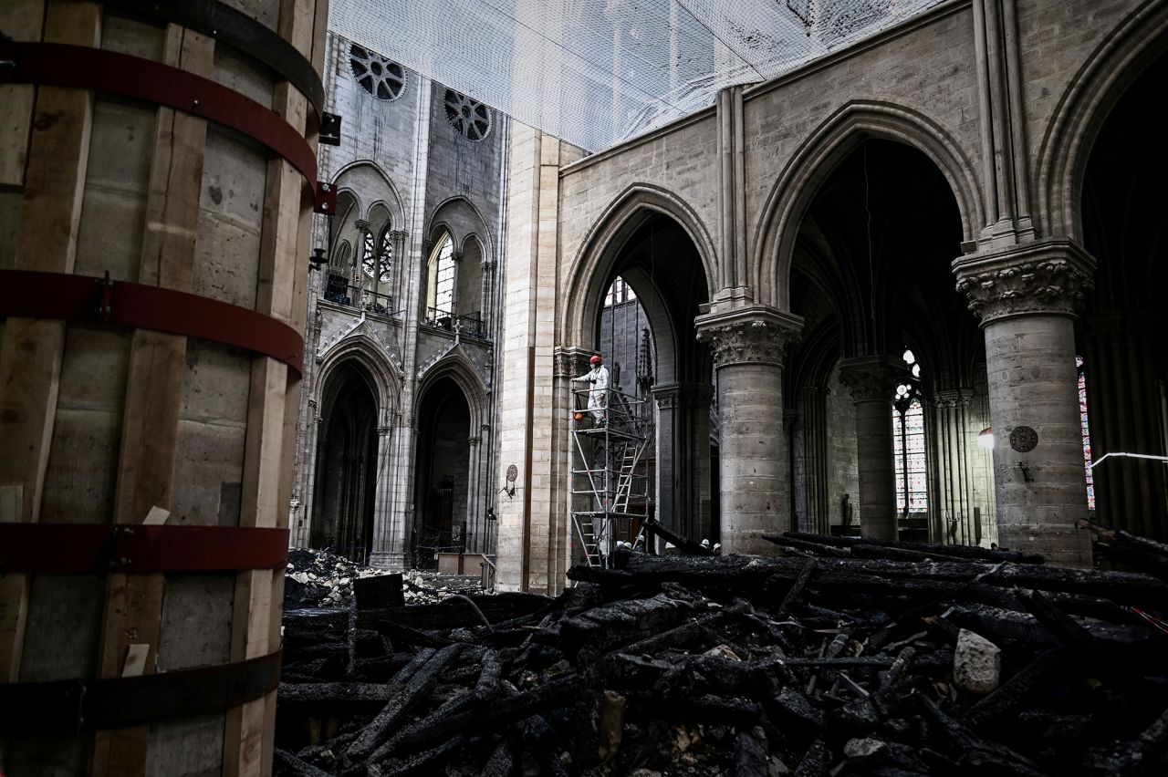 A worker stands on scaffolding in the nave near the rubble during preliminary work within Notre Dame on May 15, 2019, one month after the fire ravaged the cathedral.