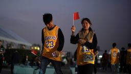 A woman and a man in LeBron James jerseys hold Chinese national flags as they walk into the Mercedes-Benz Arena before the NBA exhibition game between Brooklyn Nets and Los Angeles Lakers in Shanghai, China, on October 10, 2019.