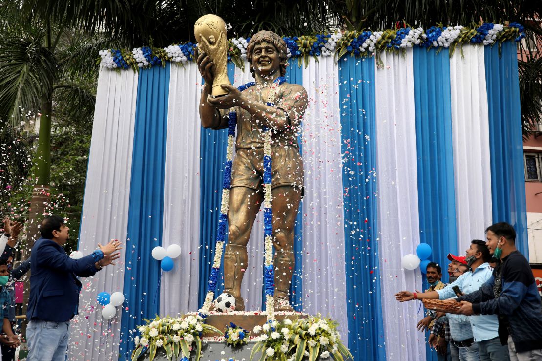 People shower flower petals on Diego Maradona's statue in Kolkata during a prayer meeting to pay tribute to him after his death in November 2020.