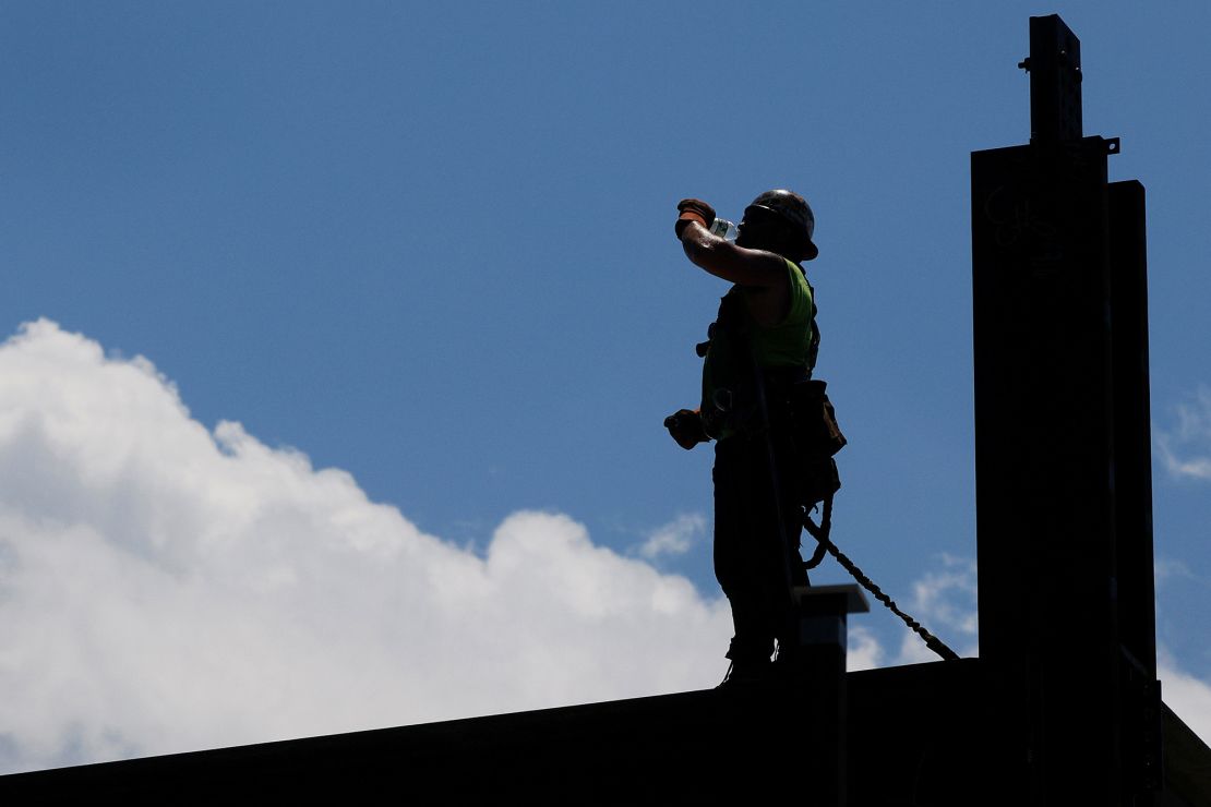 A member of the Ironworkers Local 7 union drinks a bottle of water while installing steel beams on a high-rise building under construction during a heat wave in Boston in June 2021.