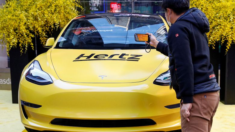 A man photographs a Hertz Tesla electric vehicle displayed during the Hertz Corporation IPO at the Nasdaq Market site in Times Square in New York City, U.S., November 9, 2021.
