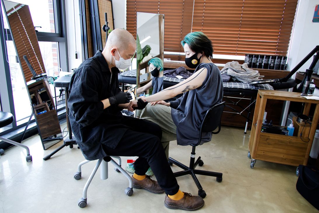Tattooist Kim Do-yoon, better known by his professional name Doy, attends to a customer in his tattoo studio in Seoul on February 15, 2022.