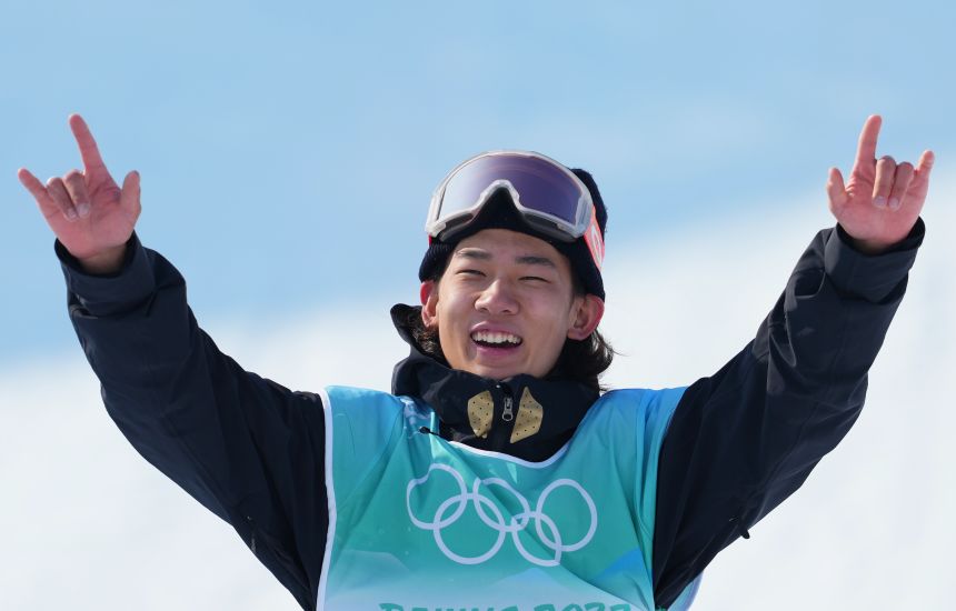 Su gestures to the home crowd as he celebrates on the Olympic podium in 2022.