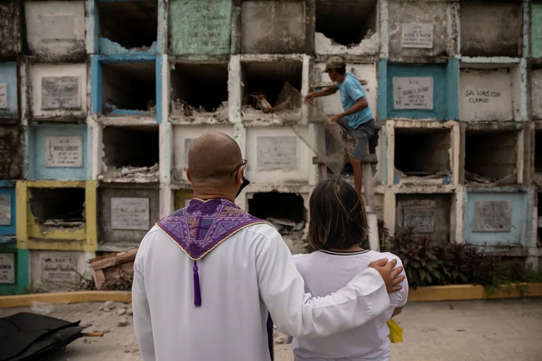 El sacerdote católico Flavie Villanueva consuela a una mujer mientras observa la exhumación de los restos de su padre en el cementerio de Navotas, Filipinas, el 8 de julio de 2021.