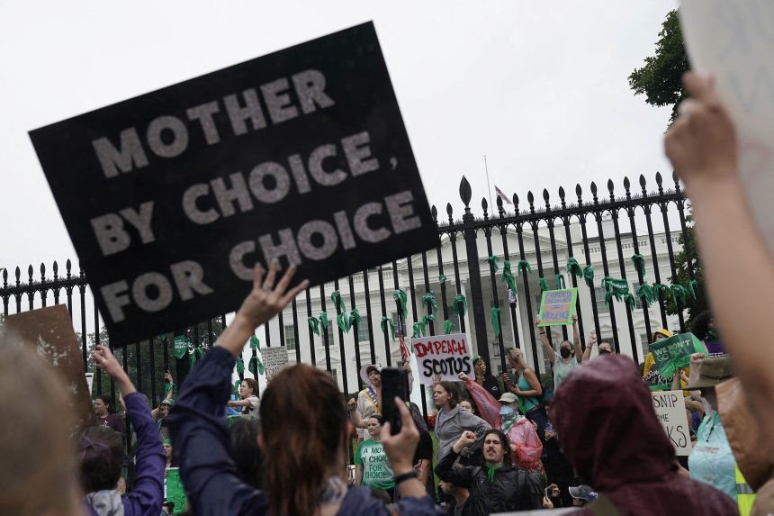 Activists hold signs outside the White House on July 9, 2022, in the wake of the Supreme Court's decision to overturn Roe v. Wade.