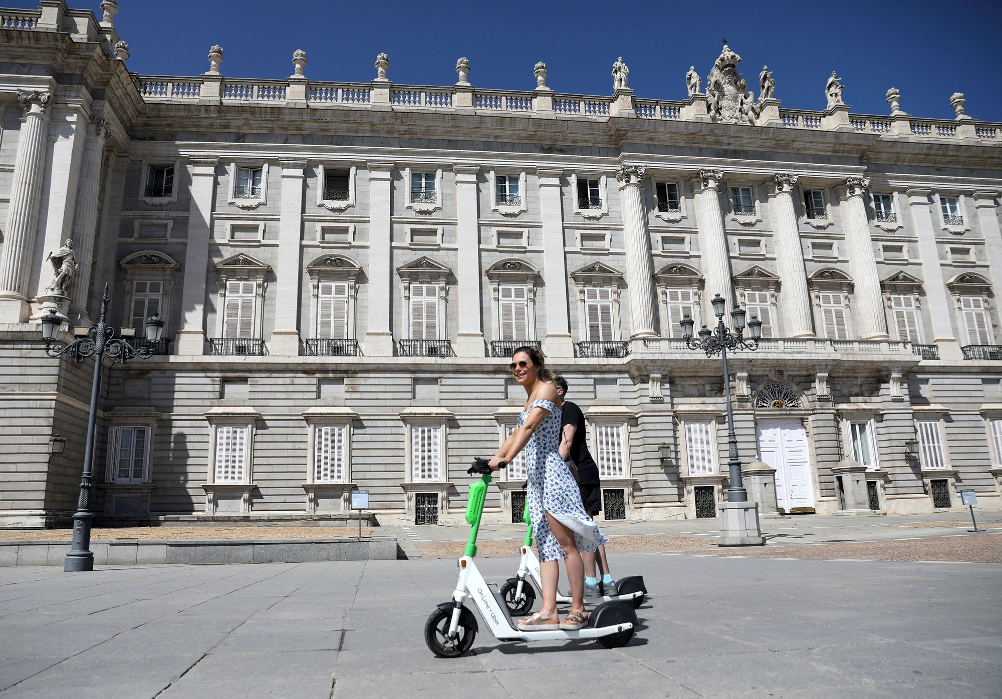 Two people ride Lime scooters near the Royal Palace in Madrid, Spain.