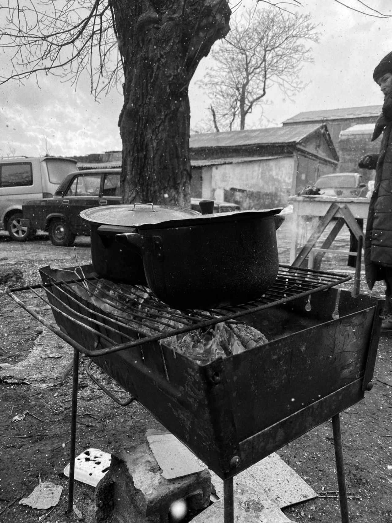 People cook on a grill on March 11. - (People charge their phones using a generator from the Red Cross on March 9.)