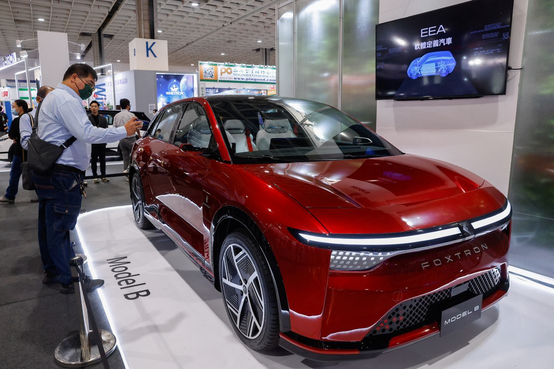 A man takes photos of the Model B car at the Foxconn booth at 2035 E-Mobility Taiwan, an annual electric and autonomous vehicle trade show in Taipei, Taiwan on April 13, 2023.