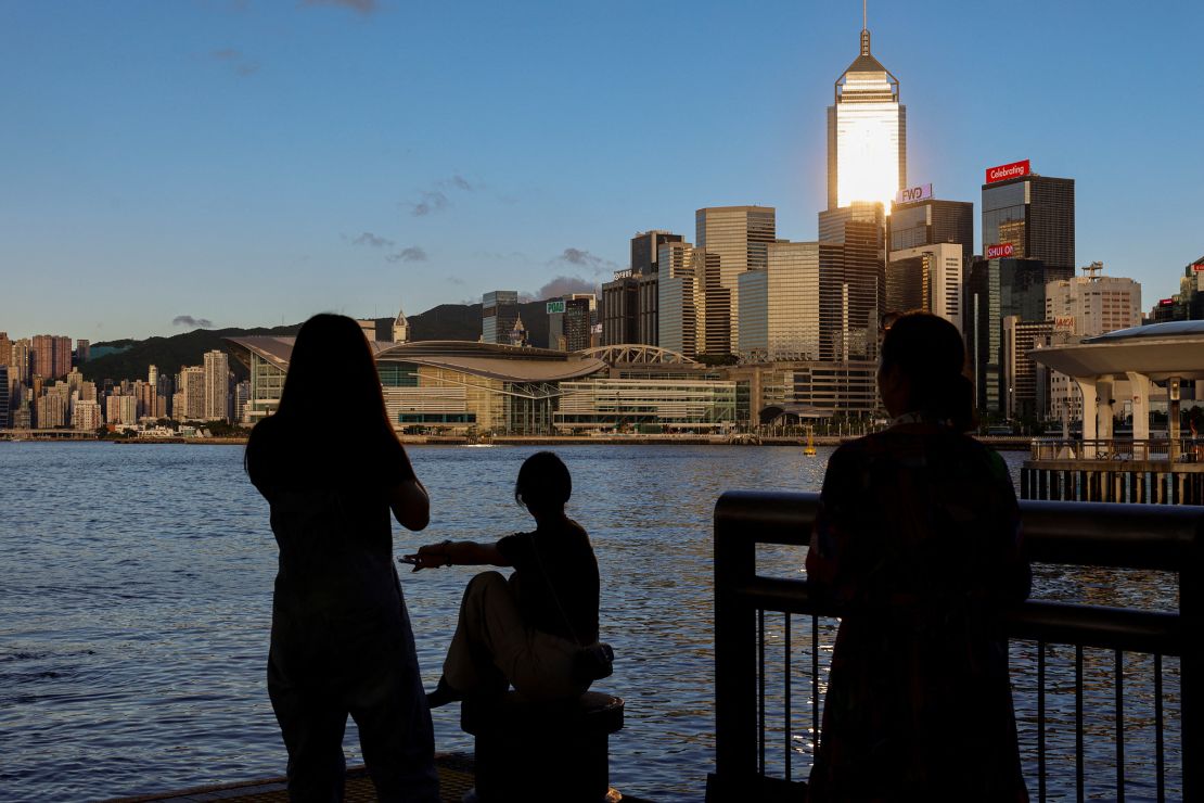 Tourists look out over Hong Kong's Victoria Harbour and the city skyline on July 10, 2023.