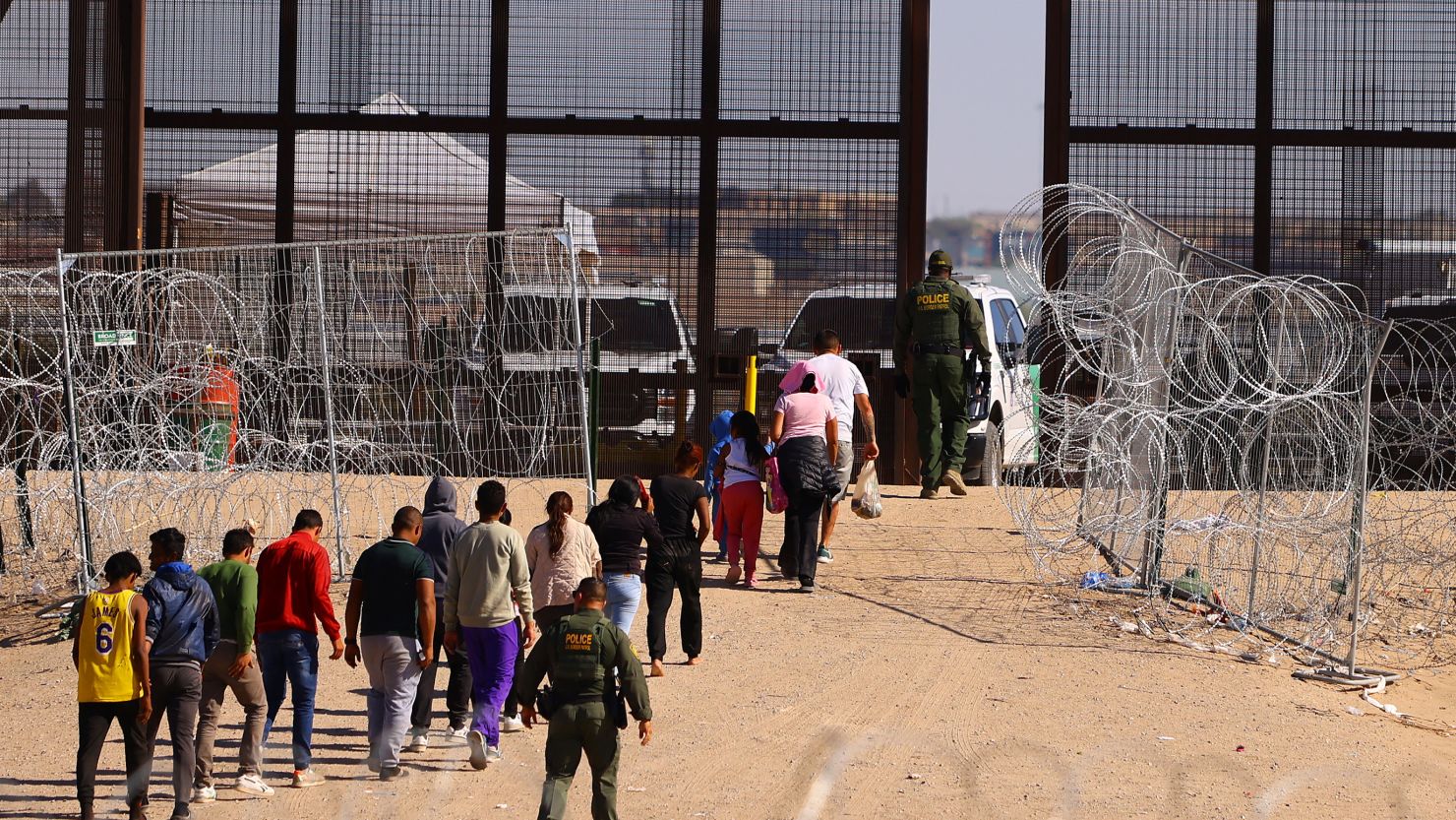 US Border Patrol agents escort migrants, who crossed the border between the United States and Mexico, through a gate in the border wall to be processed for their immigration claims, as seen from Ciudad Juarez, Mexico, in October.