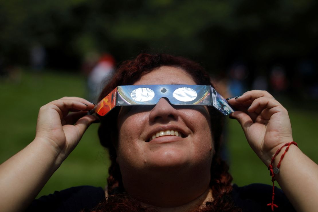 A woman uses eclipse glasses to observe an annular solar eclipse at the Bicentenario Park in Antiguo Cuscatlan, El Salvador, on October 14, 2023.