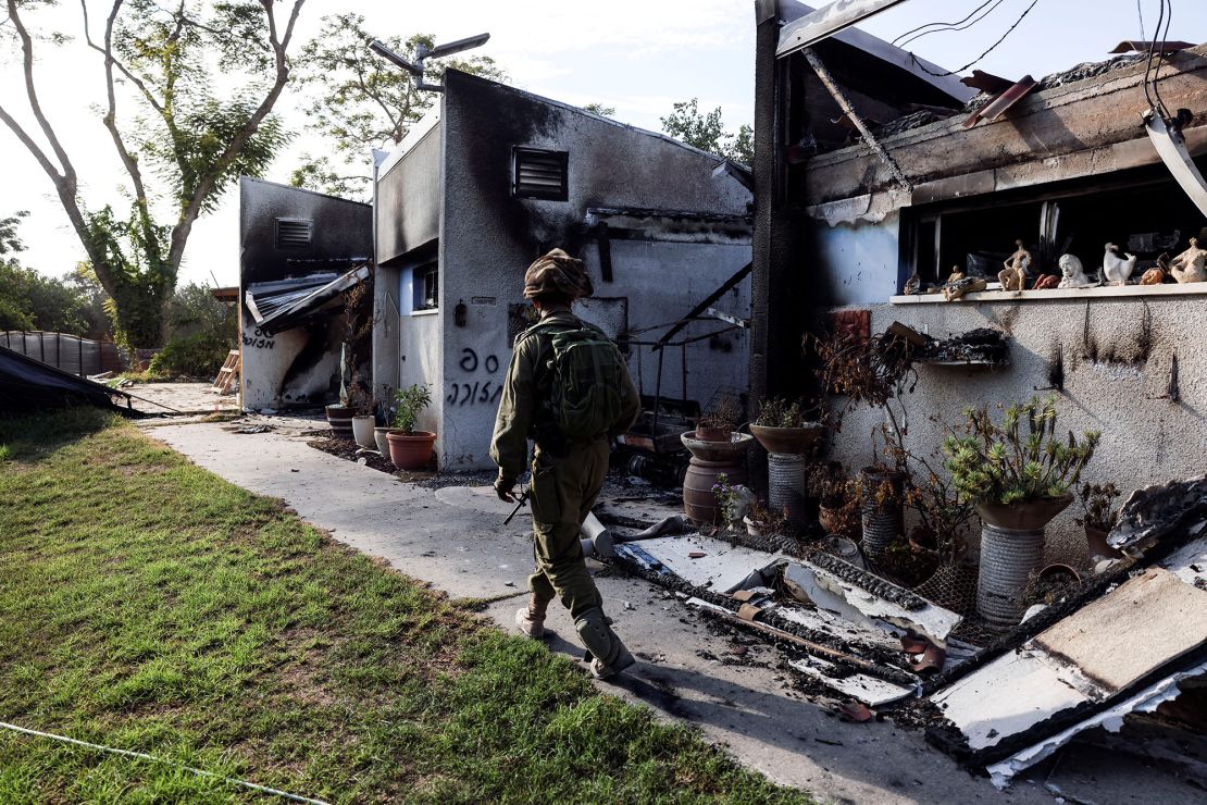 An Israeli soldier walks past the remains of a burnt houses in kibbutz Be'eri, 10 days after the October 7 attacks.