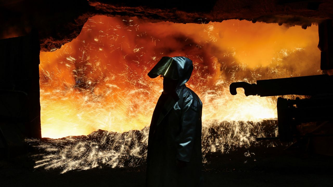 A steel worker in heat protection gear is silhouetted against the sparkling fire of Europe’s largest furnace with its daily raw iron production of 12,000 tons, at the steel plant of ThyssenKrupp in Duisburg, Germany, November 16, 2023.