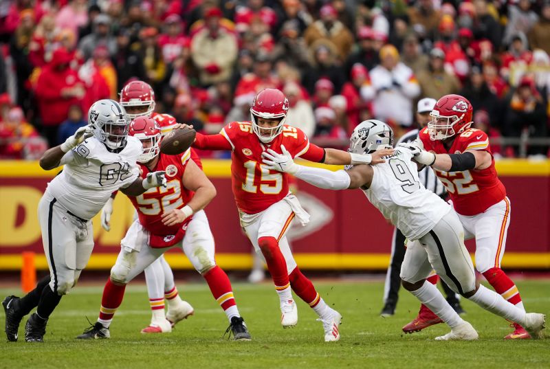 Dec 25, 2023; Kansas City, Missouri, USA; Kansas City Chiefs quarterback Patrick Mahomes (15) scrambles from Las Vegas Raiders defensive tackle Adam Butler (69) and defensive end Tyree Wilson (9) during the second half at GEHA Field at Arrowhead Stadium.