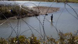 A man crosses the Rio Grande River from Mexico to collect clothing and other items left on the Texas banks of Shelby Park at the US-Mexico border in Eagle Pass, Texas, on January 12.