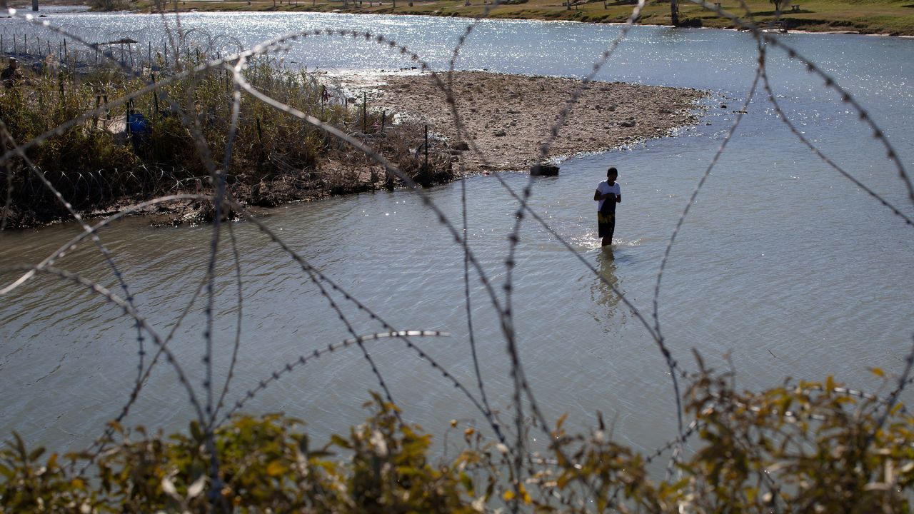 A man crosses the Rio Grande River from Mexico to collect clothing and other items left on the Texas banks of Shelby Park at the US-Mexico border in Eagle Pass, Texas, on January 12.