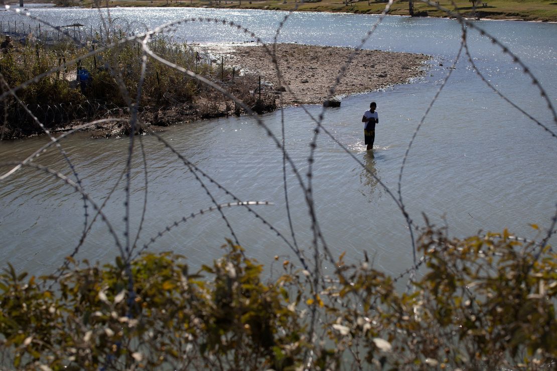 A man crosses the Rio Grande River from Mexico to collect clothing and other items left on the Texas banks of Shelby Park at the US-Mexico border in Eagle Pass, Texas, on January 12, 2024.