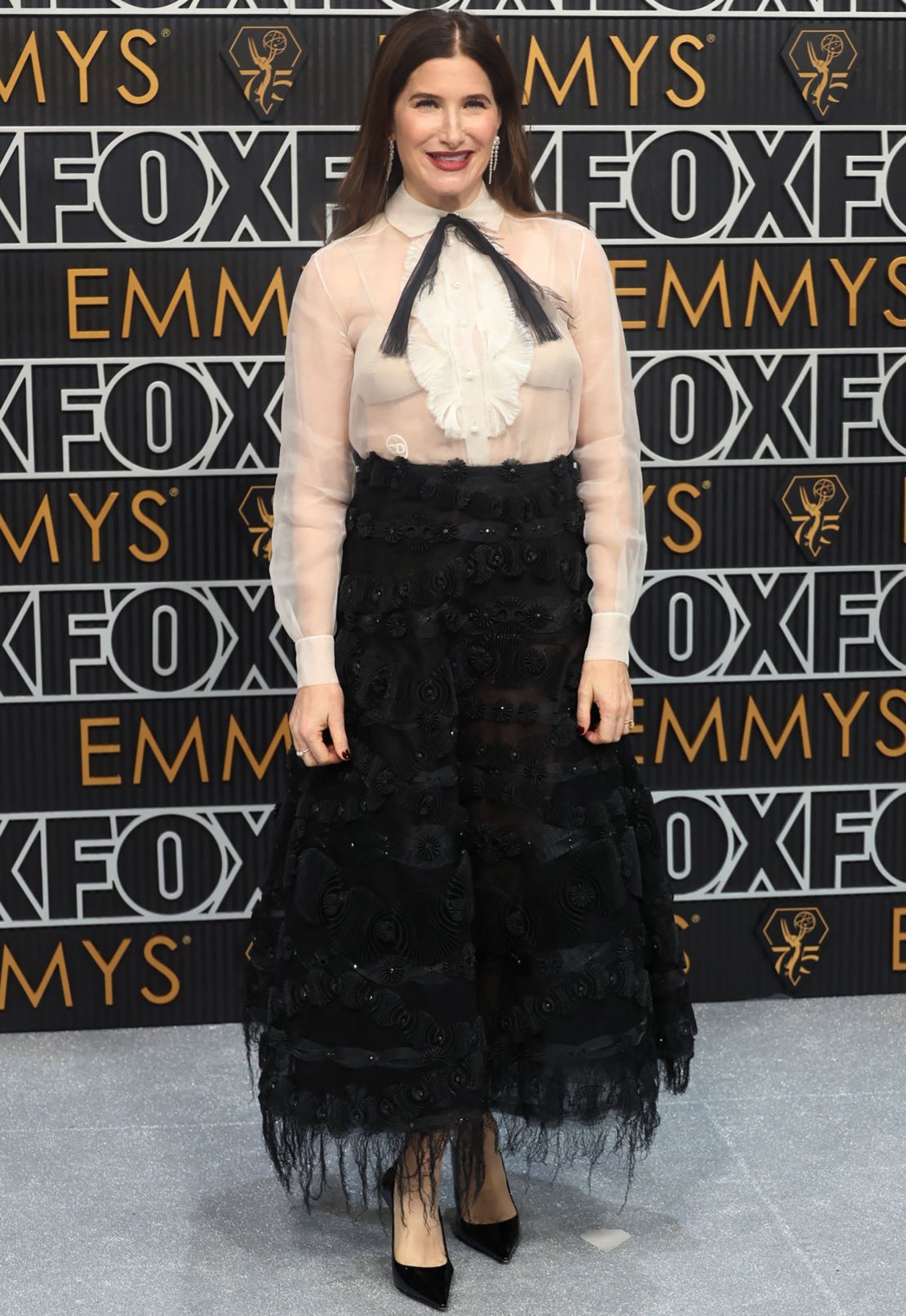 Kathryn Hahn wore Sophie Bille Brahe jewelry and a Spring-Summer 2019 Dior Haute Couture cocktail ensemble, comprised of an ivory organza bib-front shirt and black embroidered skirt.