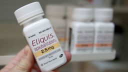 A pharmacist holds a bottle of the drug Eliquis, made by Pfizer and Bristol Myers Squibb, at a pharmacy in Provo, Utah, in January 2020. 
