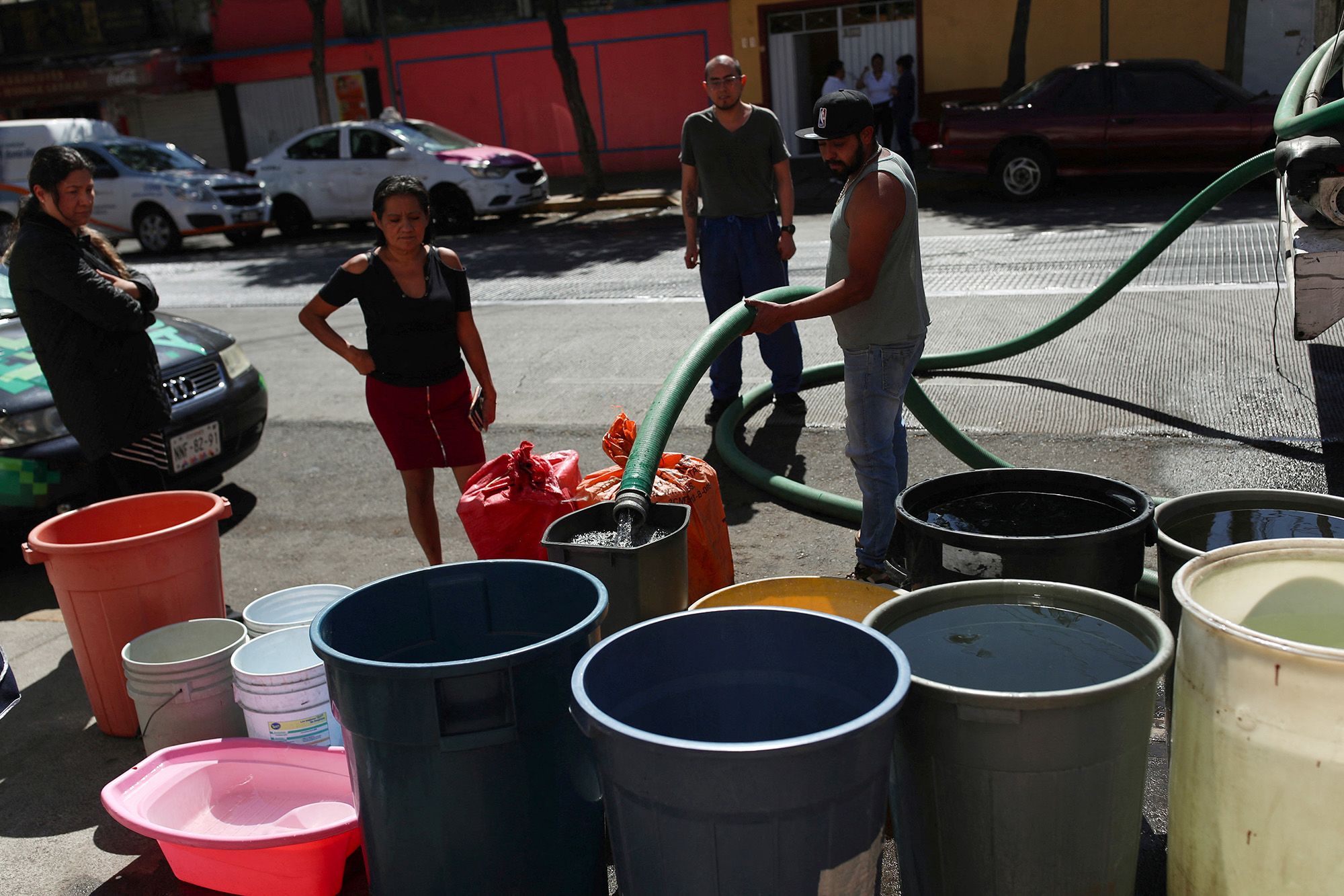 People fill buckets from a water tanker in the Azcapotzalco neighborhood in Mexico City on January 26, 2024