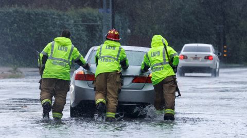 Firemen aid a vehicle through floodwater in Tarzana, in the San Fernando Valley region of Los Angeles on February 1, 2024.