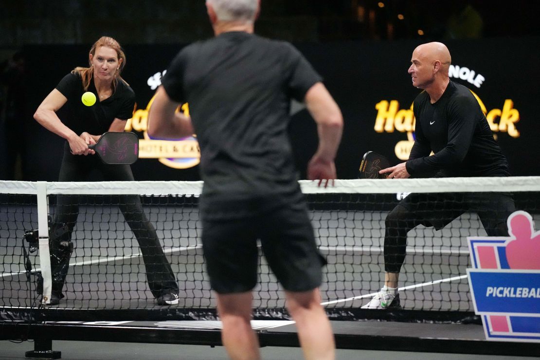 Graf returns a volley from John McEnroe as teammate Andre Agassi looks on during Pickleball Slam 2.