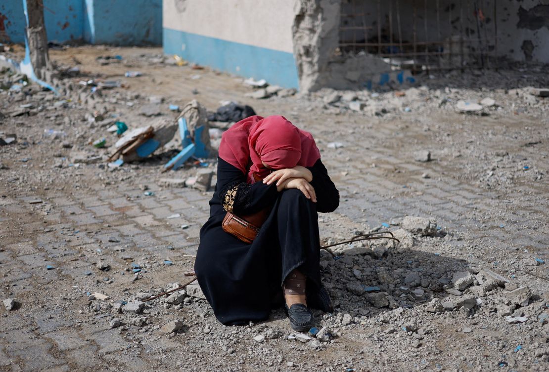 A woman rests next to a damaged building, as Palestinians arrive in Rafah after they were evacuated from Nasser hospital in Khan Younis due to the Israeli ground operation, in the southern Gaza Strip on February 15.