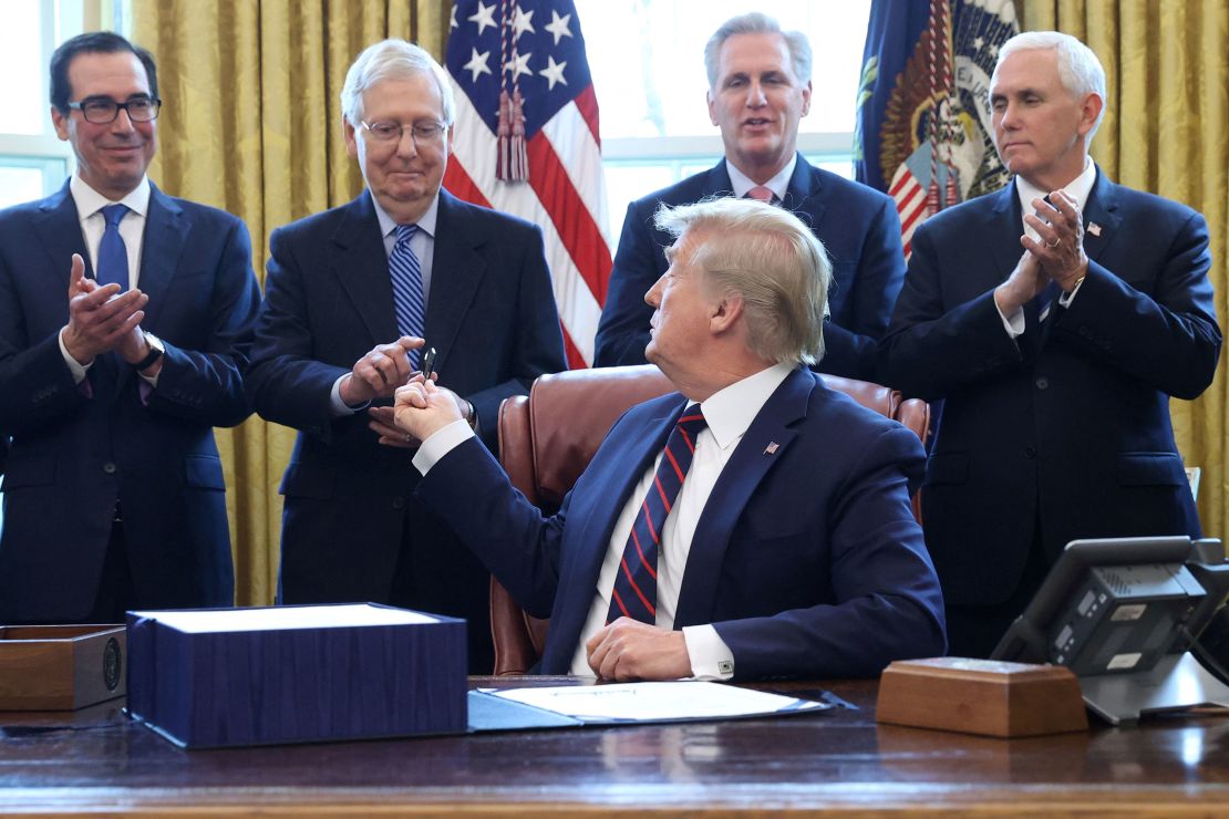 Then-President Donald Trump hands a pen to then-Senate Majority Leader Mitch McConnell after signing the $2.2 trillion coronavirus aid package bill during a signing ceremony in the Oval Office of the White House in Washington, DC, March 27, 2020.