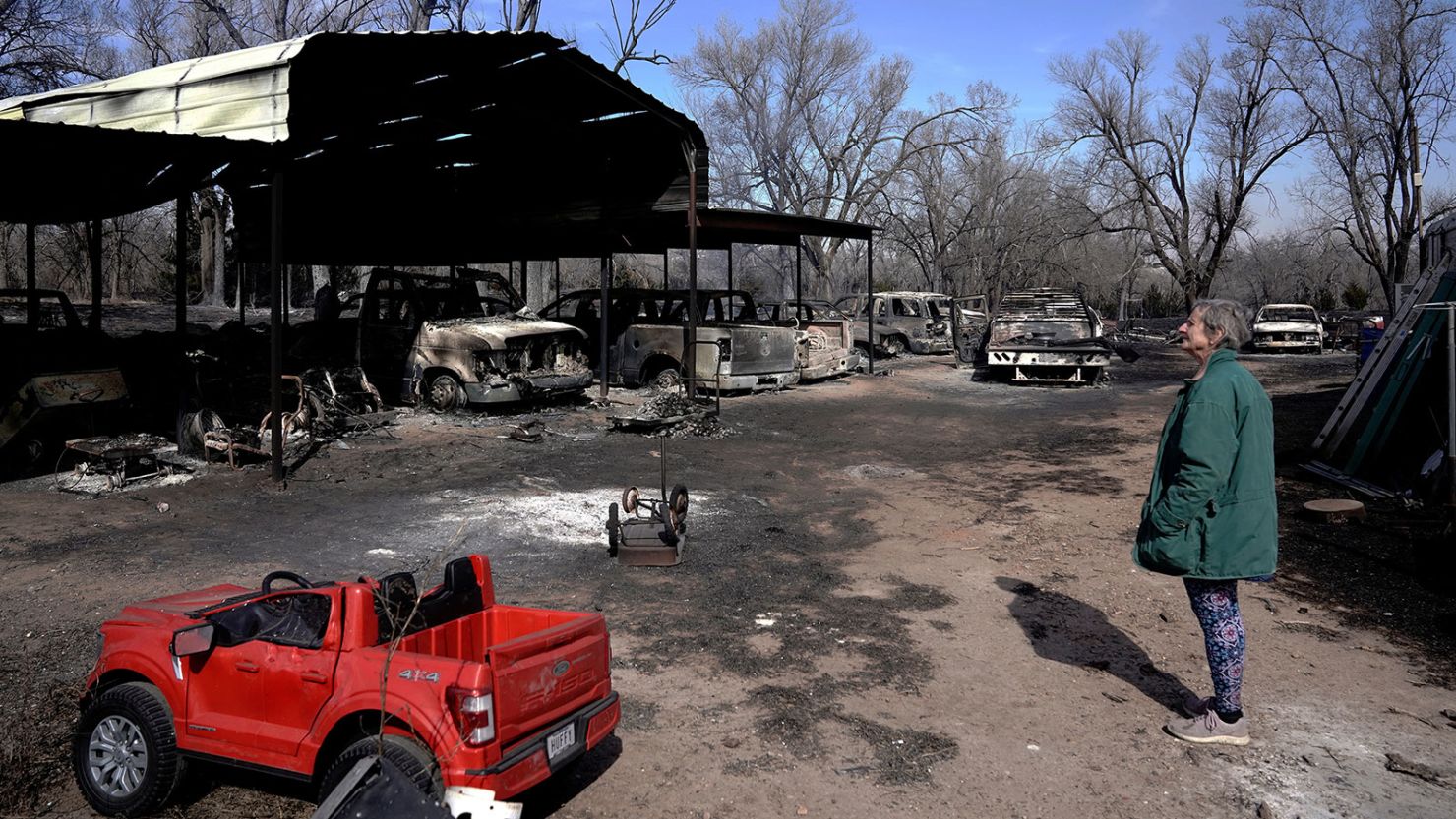 A resident of Canadian, Texas looks over vehicles destroyed on her property by the Smokehouse Creek wildfire.