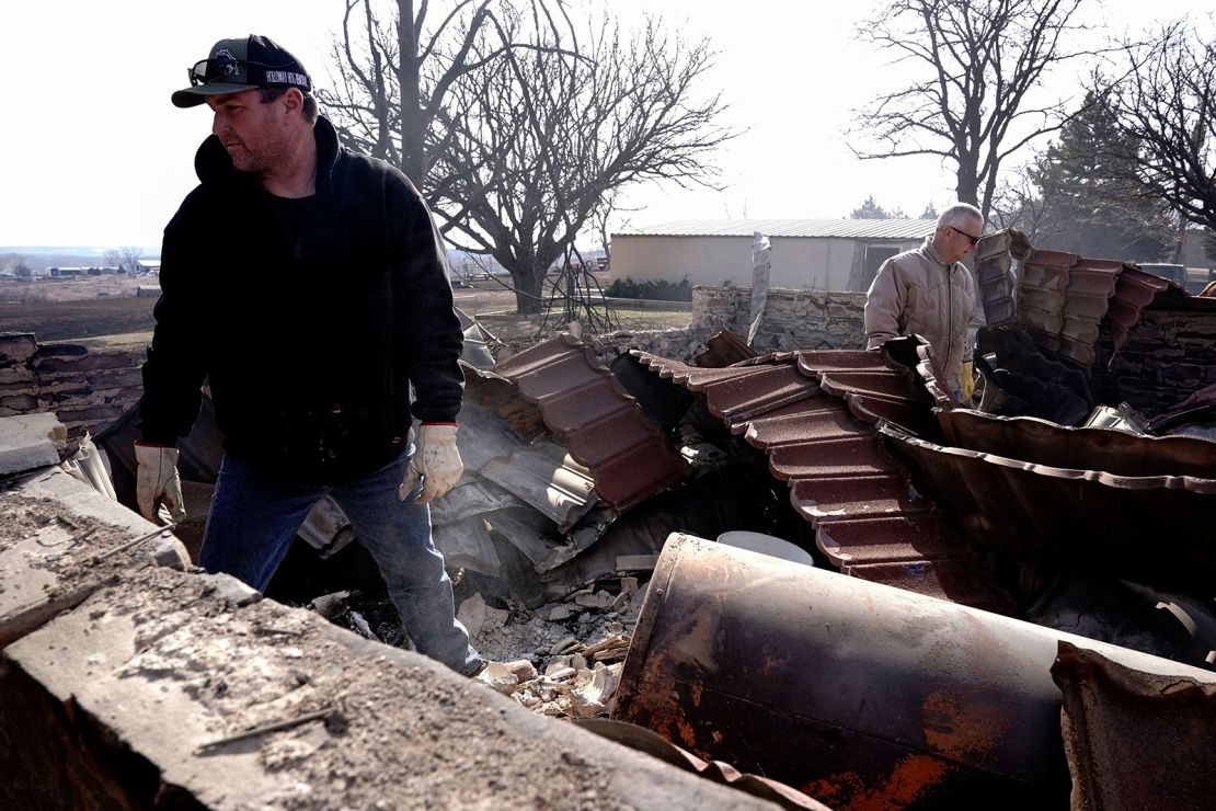 Mason Holloway and Hugh Lively sift through the remains of a relative's home destroyed by the Smokehouse Creek Fire in Canadian, Texas, on Wednesday.